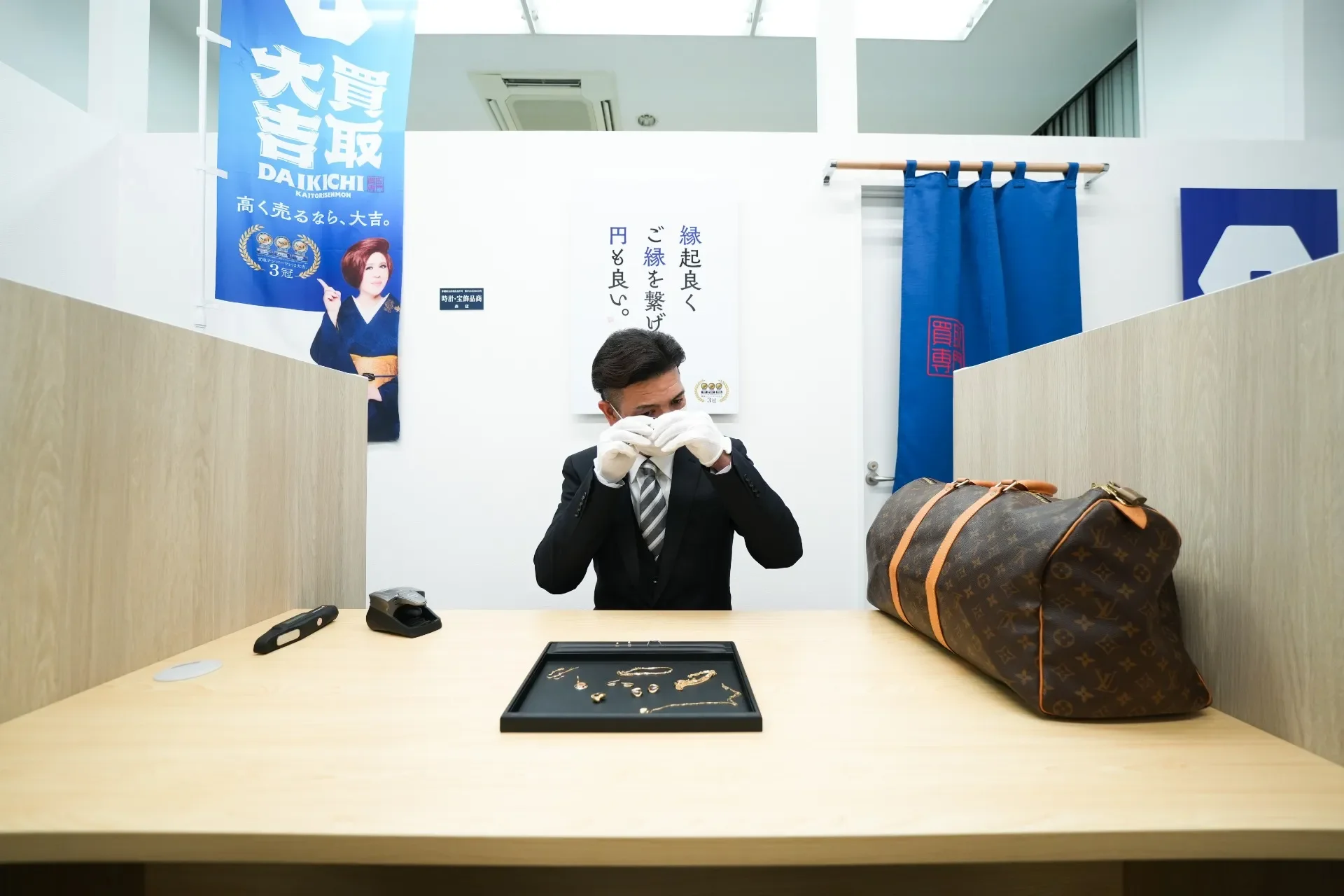 査定台でルーペを使いジュエリーを確認する手元